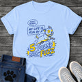 Illustrated graphic tee design of a small energetic dog leaping, with a speech bubble reading "Don't Worry, My Life Is Run by a 5 Pound Ball of Fuzz" in bold comic style type.