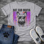 French Bulldog t-shirt with bold black block text reading Bat Ear Mafia above a Frenchie portrait wearing sunglasses, purple and orange glitch data drip background, black ink dripping below, high impact streetwear graphic
