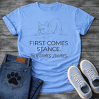 French Bulldog t-shirt with minimal continuous line art Frenchie in play bow zoomies stance, bold sans-serif text reading First Comes Stance Then Comes Zoomies, single dark ink on warm sand tee, premium clean design