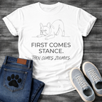 French Bulldog t-shirt with minimal continuous line art Frenchie in play bow zoomies stance, bold sans-serif text reading First Comes Stance Then Comes Zoomies, single dark ink on warm sand tee, premium clean design