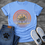 French Bulldog t-shirt with retro sunset rainbow arc, geometric compass rose with running Frenchie silhouette centered, gradient pink orange and purple tones with water reflection below, vintage adventure illustration graphic