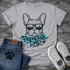 Bulldog t-shirt with street art style Frenchie wearing sunglasses reflecting a city skyline, bold electric blue graffiti text reading Frenchie Dad with drip paint effects, two-color urban graphic on warm sand tee