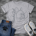 French Bulldog t-shirt with minimal continuous line art Frenchie side profile portrait, flowing script text reading Frenchie Dad alongside, single dark ink on warm sand tee, premium gallery style design