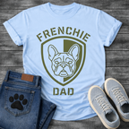 French Bulldog t-shirt with military style shield badge containing a geometric Frenchie face portrait, stencil font arched text reading Frenchie above and Dad below, single olive green ink graphic