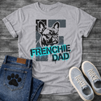 French Bulldog t-shirt with stencil-style Frenchie portrait over distressed dark block background, bold neon cyan graffiti text reading Frenchie Dad with black drip effects, high contrast urban street art graphic on warm sand tee
