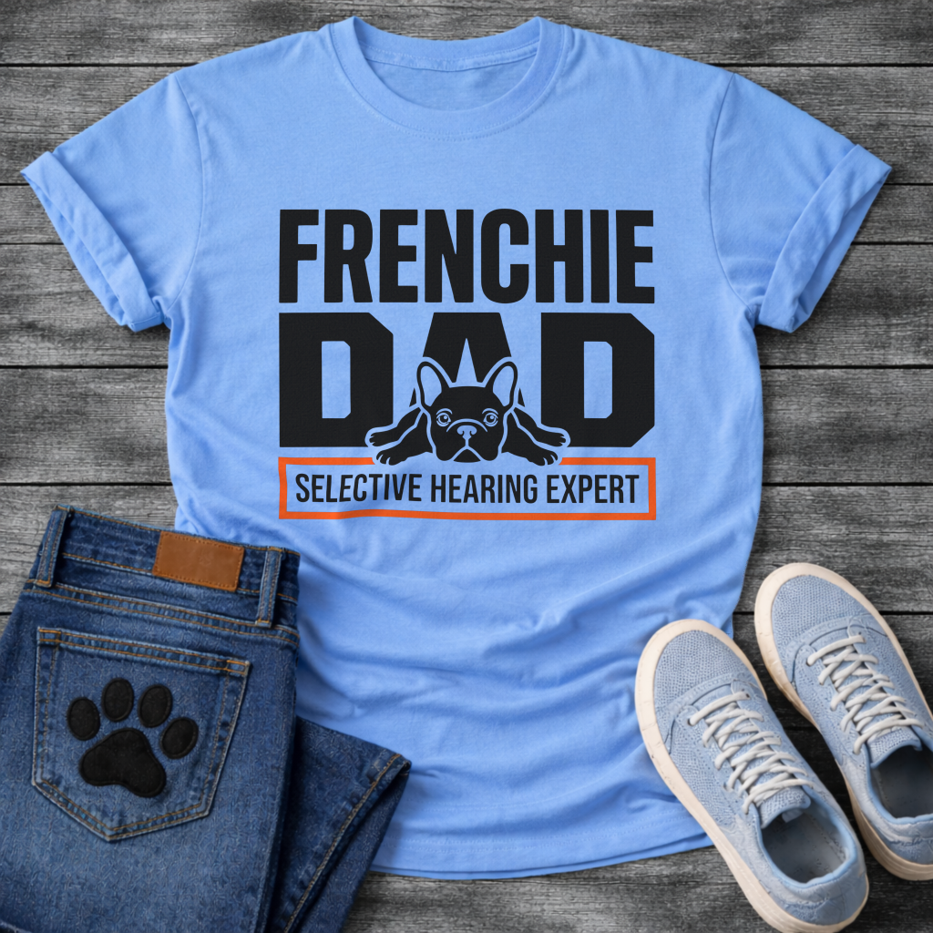 French Bulldog t-shirt with oversized bold typography reading Frenchie Dad, splooting Frenchie illustration tucked between the letters, orange bordered banner below reading Selective Hearing Expert, black and orange graphic design