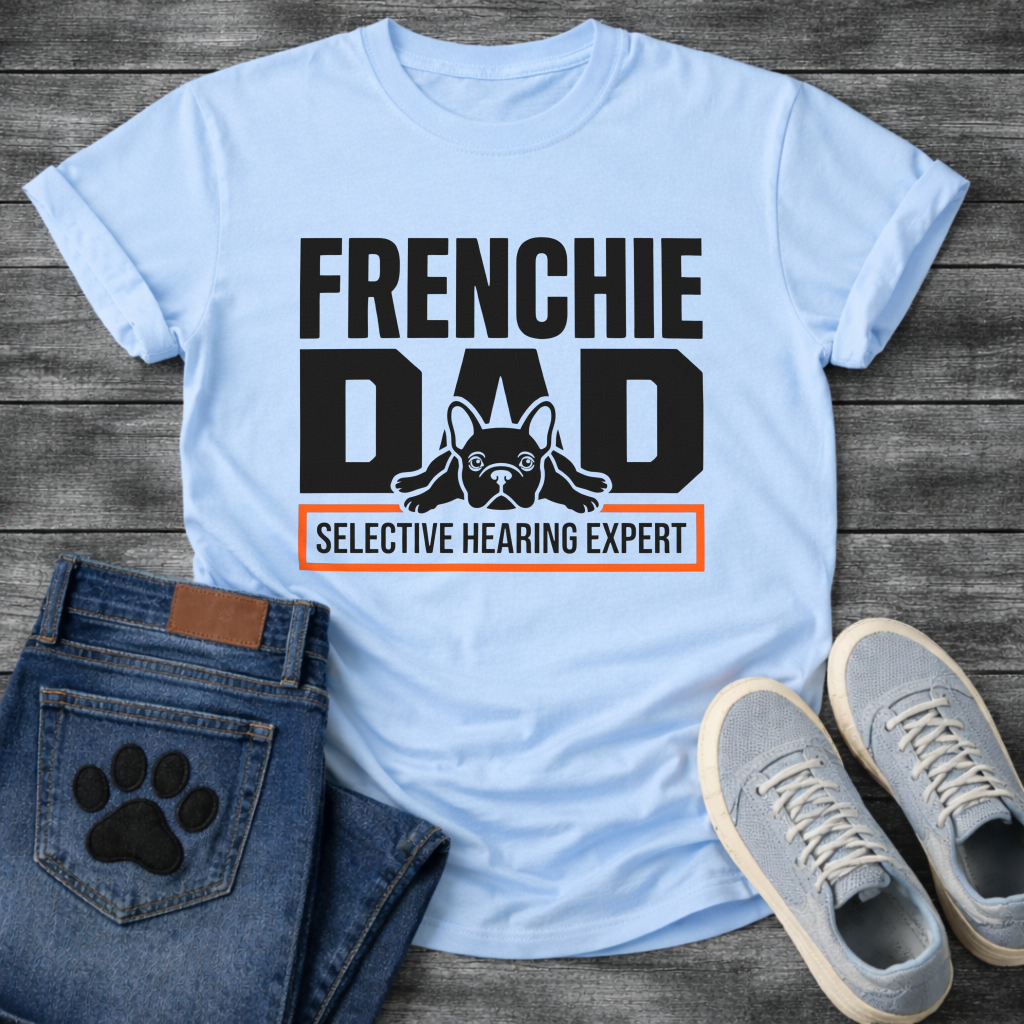 French Bulldog t-shirt with oversized bold typography reading Frenchie Dad, splooting Frenchie illustration tucked between the letters, orange bordered banner below reading Selective Hearing Expert, black and orange graphic design