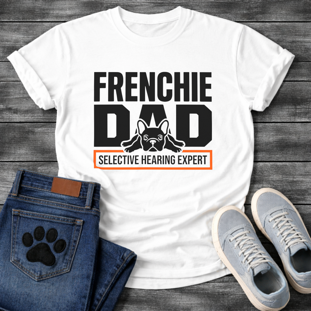 French Bulldog t-shirt with oversized bold typography reading Frenchie Dad, splooting Frenchie illustration tucked between the letters, orange bordered banner below reading Selective Hearing Expert, black and orange graphic design