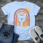 French Bulldog t-shirt with peaceful Frenchie face eyes closed centered in a boho rainbow arch, wildflower and botanical line art on either side, muted purple terracotta gold and cream tones, abstract circles in background, soft boho illustration no text