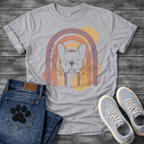 French Bulldog t-shirt with peaceful Frenchie face eyes closed centered in a boho rainbow arch, wildflower and botanical line art on either side, muted purple terracotta gold and cream tones, abstract circles in background, soft boho illustration no text
