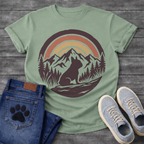 French Bulldog t-shirt with circular badge illustration, Frenchie silhouette sitting on a rocky trail surrounded by pine trees and mountain peaks, retro sunset stripe arch above in terracotta and gold, deep plum border, distressed vintage texture, no text