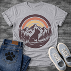 French Bulldog t-shirt with circular badge illustration, Frenchie silhouette sitting on a rocky trail surrounded by pine trees and mountain peaks, retro sunset stripe arch above in terracotta and gold, deep plum border, distressed vintage texture, no text