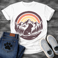 French Bulldog t-shirt with circular badge illustration, Frenchie silhouette sitting on a rocky trail surrounded by pine trees and mountain peaks, retro sunset stripe arch above in terracotta and gold, deep plum border, distressed vintage texture, no text