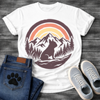 French Bulldog t-shirt with circular badge illustration, Frenchie silhouette sitting on a rocky trail surrounded by pine trees and mountain peaks, retro sunset stripe arch above in terracotta and gold, deep plum border, distressed vintage texture, no text