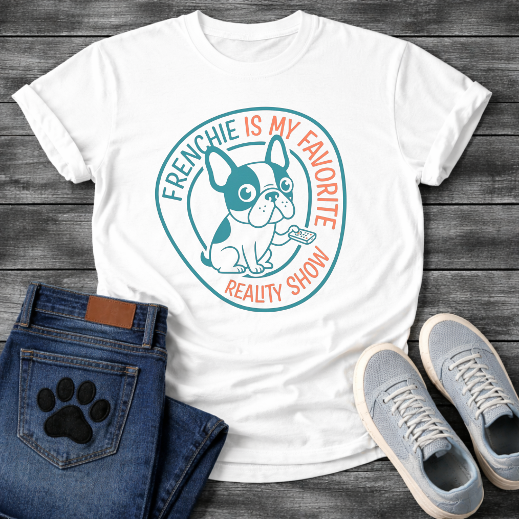 French Bulldog t-shirt with circular badge design, cartoon Frenchie holding a TV remote, teal and coral circular text reading Frenchie Is My Favorite Reality Show, two-color retro emblem on warm sand tee
