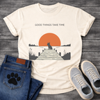French Bulldog t-shirt with Frenchie silhouette sitting on a wooden dock facing a large terracotta sunset over water, reeds and shoreline on either side, text above reading Good Things Take Time, two-color vintage landscape illustration