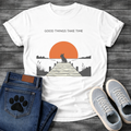 French Bulldog t-shirt with Frenchie silhouette sitting on a wooden dock facing a large terracotta sunset over water, reeds and shoreline on either side, text above reading Good Things Take Time, two-color vintage landscape illustration