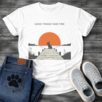 French Bulldog t-shirt with Frenchie silhouette sitting on a wooden dock facing a large terracotta sunset over water, reeds and shoreline on either side, text above reading Good Things Take Time, two-color vintage landscape illustration