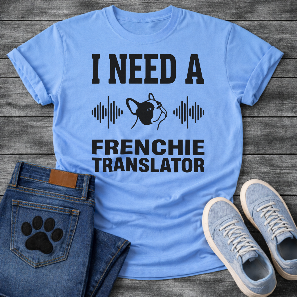 French Bulldog t-shirt with bold collegiate typography reading I Need a Frenchie Translator, black Frenchie face silhouette flanked by sound wave graphics, single dark ink on warm sand tee, clean graphic design