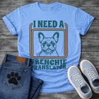 French Bulldog t-shirt with retro 70s groovy typography reading I Need a Frenchie Translator, detailed Frenchie portrait centered in teal and orange rounded rectangle frame, two-color retro illustration on warm sand tee