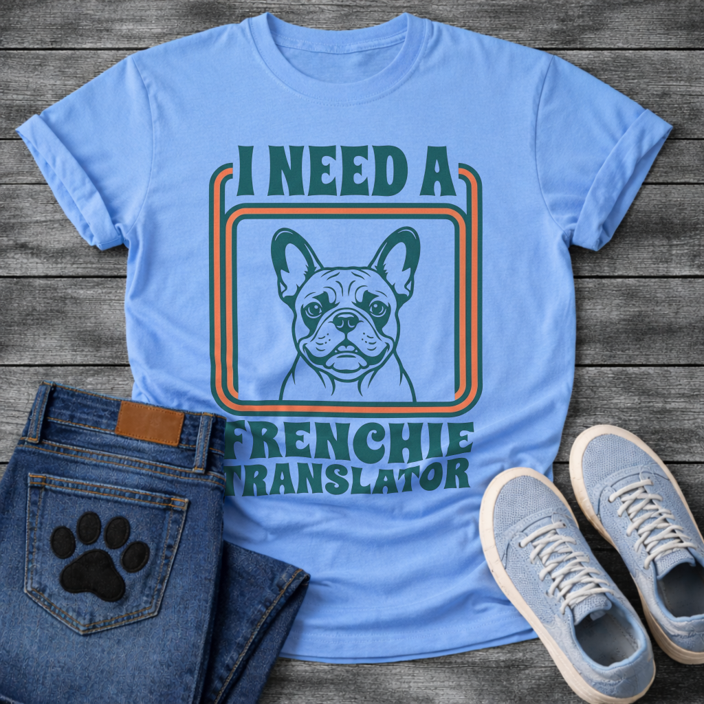 French Bulldog t-shirt with retro 70s groovy typography reading I Need a Frenchie Translator, detailed Frenchie portrait centered in teal and orange rounded rectangle frame, two-color retro illustration on warm sand tee
