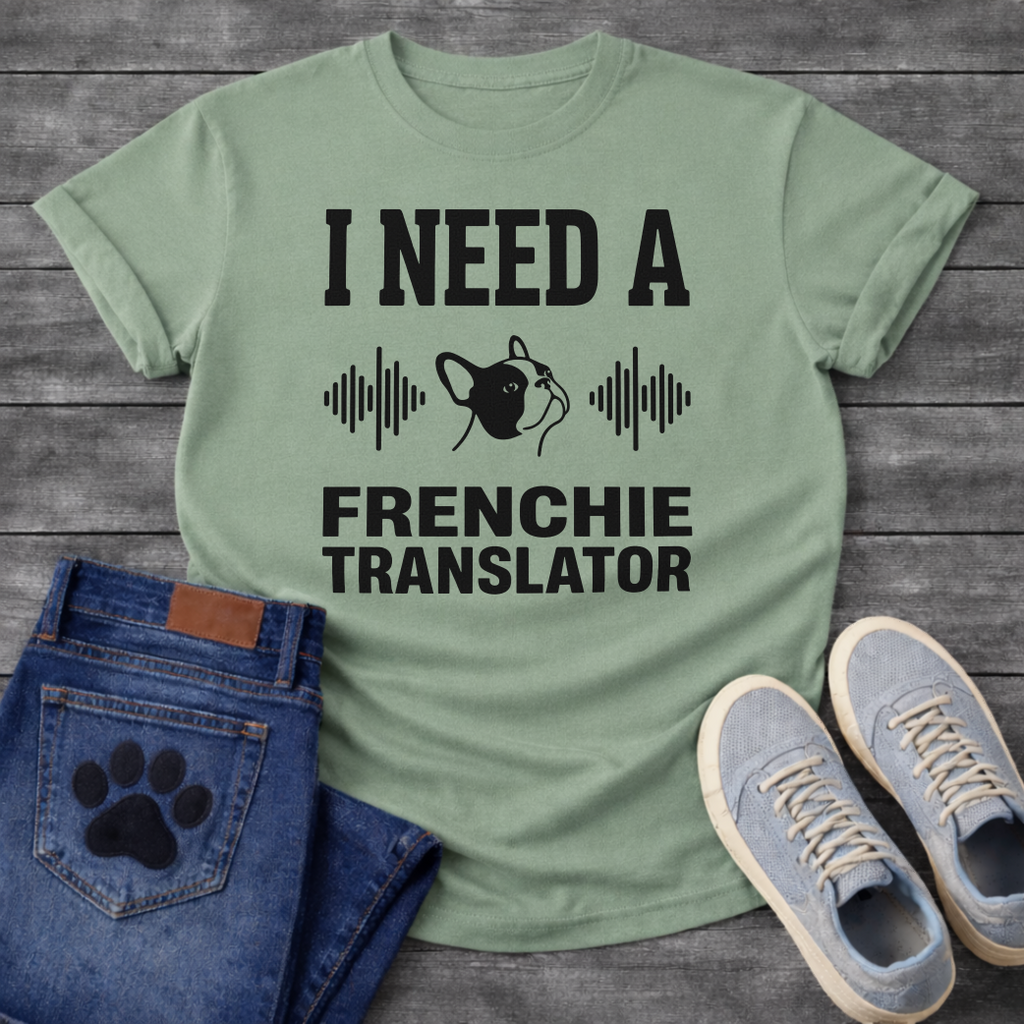 French Bulldog t-shirt with bold collegiate typography reading I Need a Frenchie Translator, black Frenchie face silhouette flanked by sound wave graphics, single dark ink on warm sand tee, clean graphic design