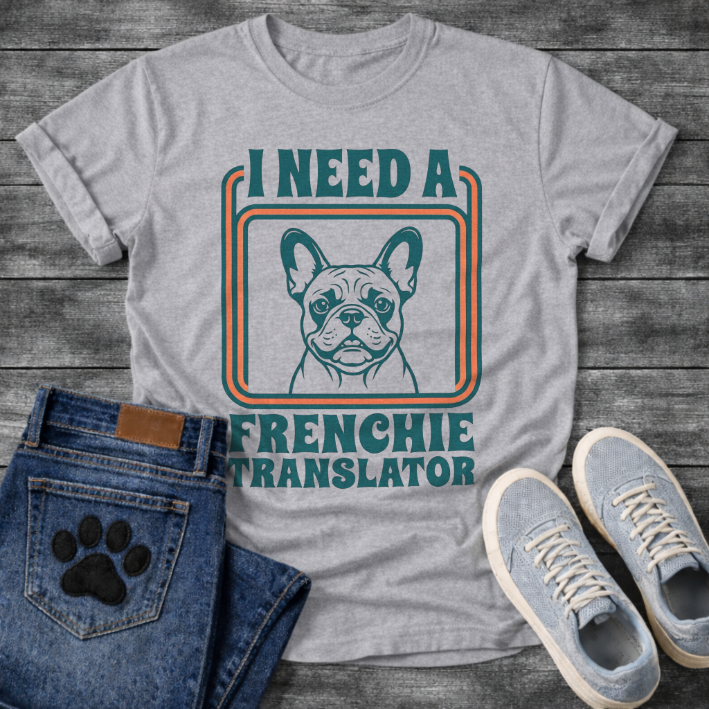 French Bulldog t-shirt with retro 70s groovy typography reading I Need a Frenchie Translator, detailed Frenchie portrait centered in teal and orange rounded rectangle frame, two-color retro illustration on warm sand tee