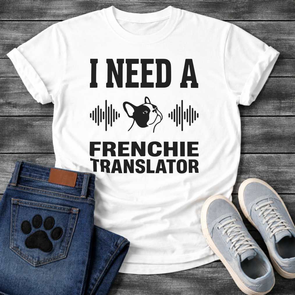 French Bulldog t-shirt with bold collegiate typography reading I Need a Frenchie Translator, black Frenchie face silhouette flanked by sound wave graphics, single dark ink on warm sand tee, clean graphic design