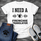 French Bulldog t-shirt with bold collegiate typography reading I Need a Frenchie Translator, black Frenchie face silhouette flanked by sound wave graphics, single dark ink on warm sand tee, clean graphic design