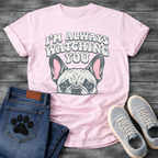 French Bulldog t-shirt with retro 70s bubble typography reading I'm Always Watching You above a peeking Frenchie face with pink inner ears, vintage halftone illustration on warm sand tee, groovy retro style