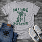 French Bulldog t-shirt with retro groovy arched text reading Not a Lapdog above a detailed Frenchie illustration mid-vocalization beside a vintage microphone, bold text below reading Loud and Proud, single forest green ink graphic