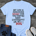 Stamped newspaper style graphic tee design reading "My Life Is Arranged Solely for the Comfort and Convenience of My Dog," with "Solely" and "Dog" highlighted in red, plus two small paw prints.