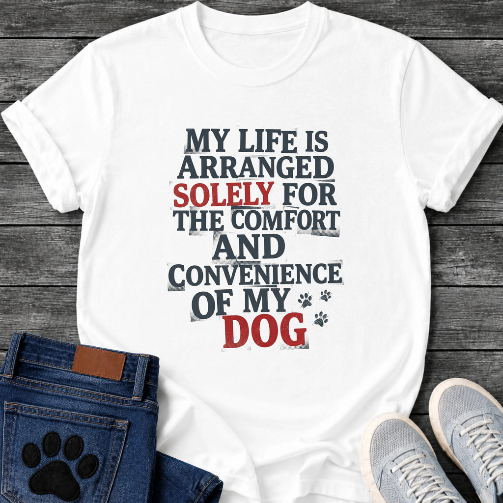Stamped newspaper style graphic tee design reading "My Life Is Arranged Solely for the Comfort and Convenience of My Dog," with "Solely" and "Dog" highlighted in red, plus two small paw prints.