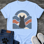 French Bulldog t-shirt with Frenchie silhouette seen from behind centered in a wavy layered landscape of slate blue and terracotta, cream moon rising behind the head, arched frame above, heavy crackle distressed texture throughout, no text earthy art graphic