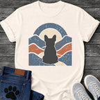 French Bulldog t-shirt with Frenchie silhouette seen from behind centered in a wavy layered landscape of slate blue and terracotta, cream moon rising behind the head, arched frame above, heavy crackle distressed texture throughout, no text earthy art graphic