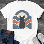 French Bulldog t-shirt with Frenchie silhouette seen from behind centered in a wavy layered landscape of slate blue and terracotta, cream moon rising behind the head, arched frame above, heavy crackle distressed texture throughout, no text earthy art graphic