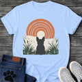 French Bulldog t-shirt with Frenchie silhouette seen from behind sitting in dark green botanical cattails and grass, cream circle moon rising behind the head, bold concentric terracotta arch above, distressed torn edge ground texture, no text boho art graphic
