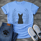 French Bulldog t-shirt with Frenchie silhouette seen from behind centered in a wide open navy line art botanical scene, tall reeds and cattails sweeping in from both sides, rippling water and distant mountain horizon ahead, no text refined nature illustration