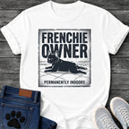 French Bulldog t-shirt with vintage distressed poster frame, bold oversized text reading Frenchie Owner above a splooting Frenchie lying flat on tile floor, bold banner text below reading Permanently Indoors, single dark ink halftone graphic with heavy crackle texture