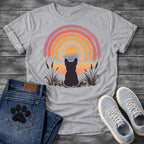 French Bulldog t-shirt with Frenchie silhouette seen from behind sitting in ink wash grass and cattails, soft watercolor sunset glow below, concentric brushstroke rainbow arch above in lavender coral orange and gold, no text painterly watercolor art graphic