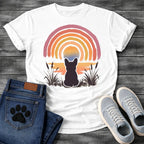 French Bulldog t-shirt with Frenchie silhouette seen from behind sitting in ink wash grass and cattails, soft watercolor sunset glow below, concentric brushstroke rainbow arch above in lavender coral orange and gold, no text painterly watercolor art graphic