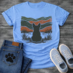 French Bulldog t-shirt with Frenchie silhouette seen from behind with cream outline sitting in grass and shallow water, bold woodcut style wavy landscape in forest green and terracotta behind, heavy distressed texture throughout, no text earthy art graphic