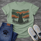 French Bulldog t-shirt with Frenchie silhouette seen from behind with cream outline sitting in grass and shallow water, bold woodcut style wavy landscape in forest green and terracotta behind, heavy distressed texture throughout, no text earthy art graphic