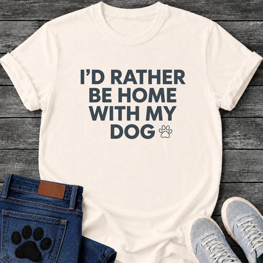 Bold centered graphic tee design reading "I'd Rather Be Home With My Dog," with a small outlined paw print beside the text.