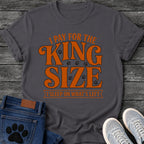 Bold vintage style graphic tee design reading "I Pay for the King Size, I Sleep on What's Left," in orange type with scattered paw prints and a banner underline.