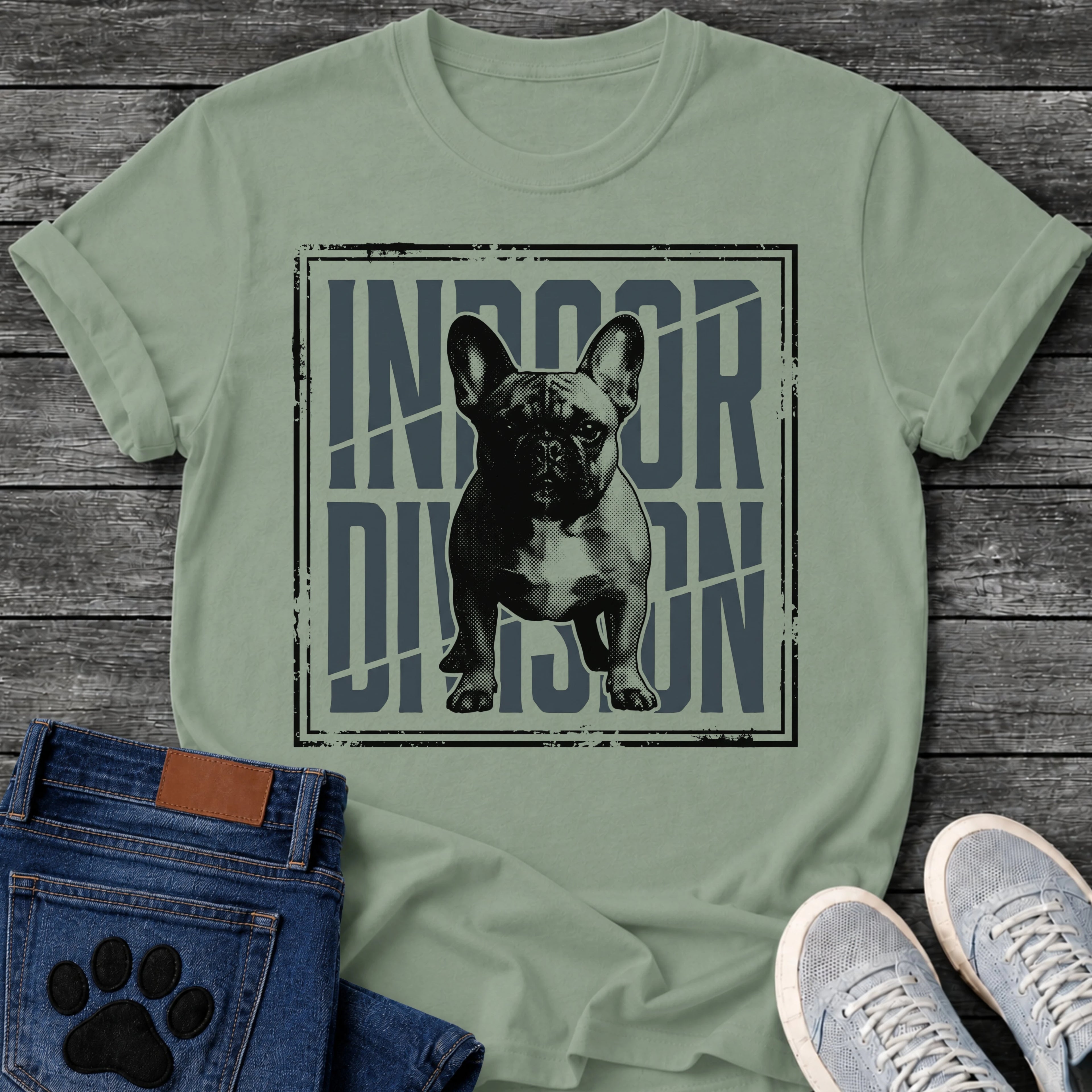 French Bulldog t-shirt with halftone Frenchie standing full body facing forward, oversized condensed slate blue text reading Indoor Division behind the portrait, diagonal slash detail, heavy distressed double border frame, black and slate two-color graphic
