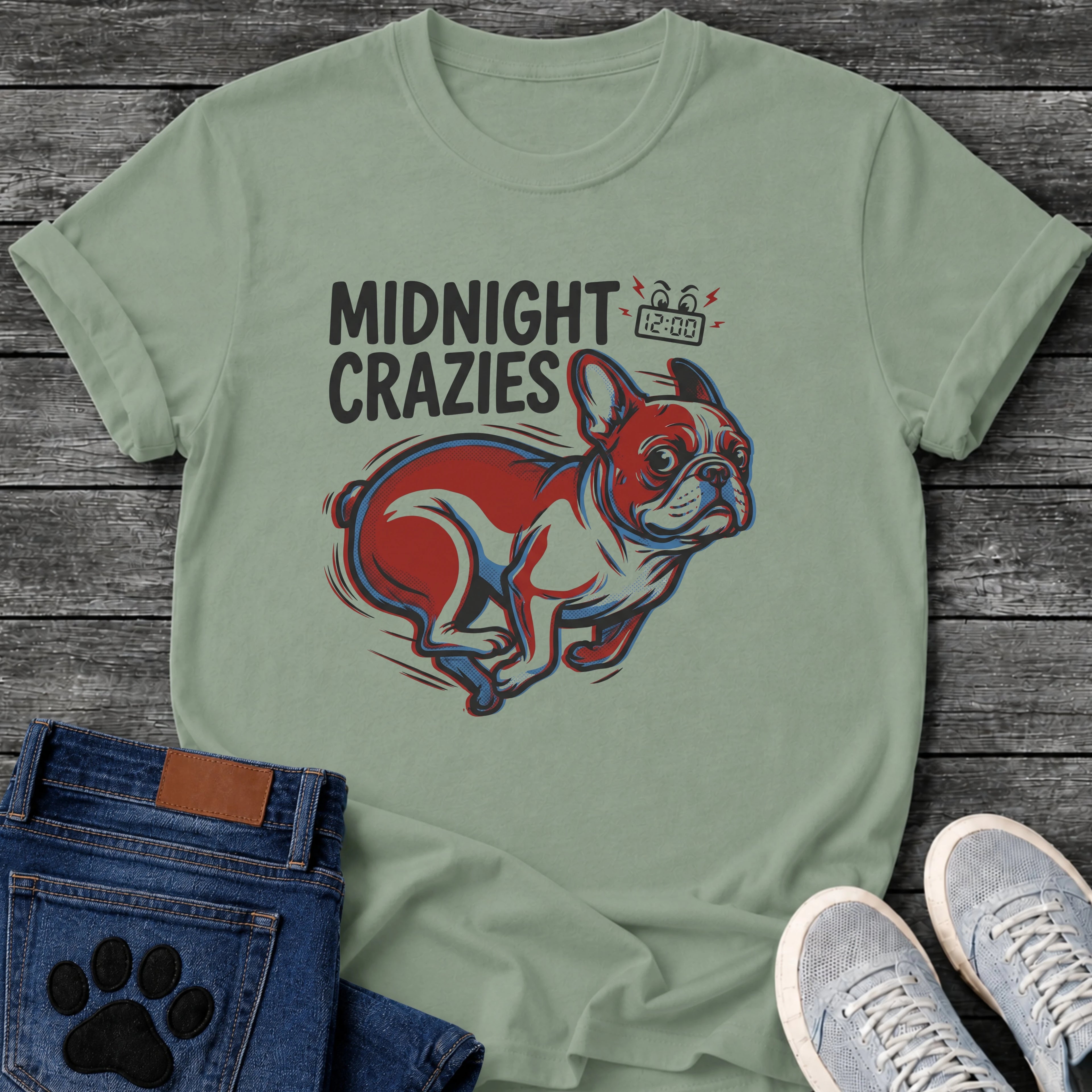 French Bulldog t-shirt with bold retro comic text reading Midnight Crazies upper left, animated alarmed clock showing 12:00 with lightning bolts and cartoon eyes, large red and blue halftone Frenchie running at full speed, speed lines throughout