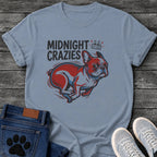 French Bulldog t-shirt with bold retro comic text reading Midnight Crazies upper left, animated alarmed clock showing 12:00 with lightning bolts and cartoon eyes, large red and blue halftone Frenchie running at full speed, speed lines throughout