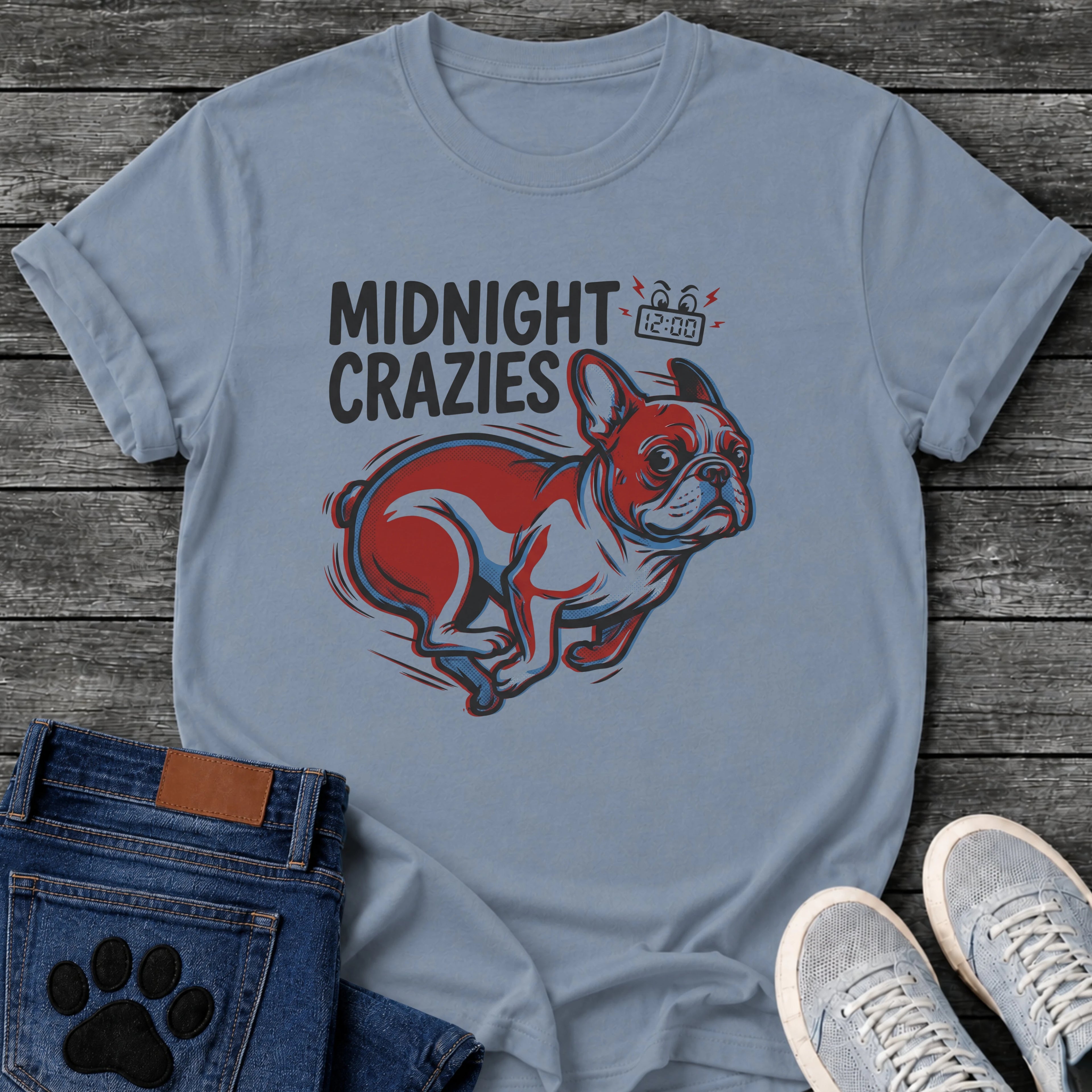 French Bulldog t-shirt with bold retro comic text reading Midnight Crazies upper left, animated alarmed clock showing 12:00 with lightning bolts and cartoon eyes, large red and blue halftone Frenchie running at full speed, speed lines throughout