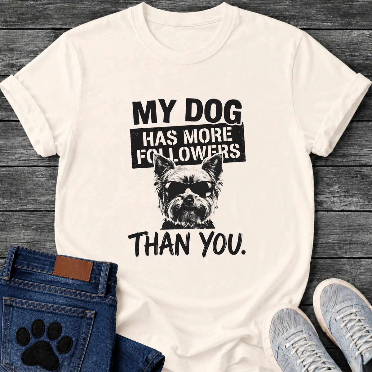 Bold graphic tee design featuring a small dog wearing sunglasses, with stamped text reading "My Dog Has More Followers Than You."